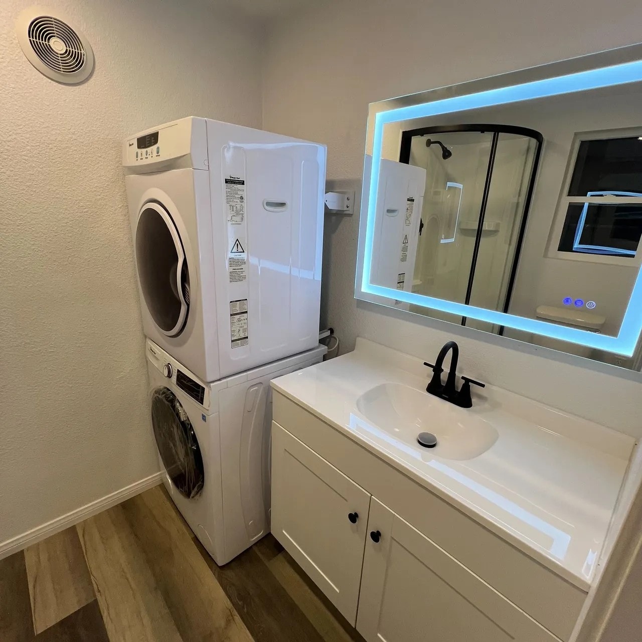 Container home bathroom with stacked laundry and LED mirror